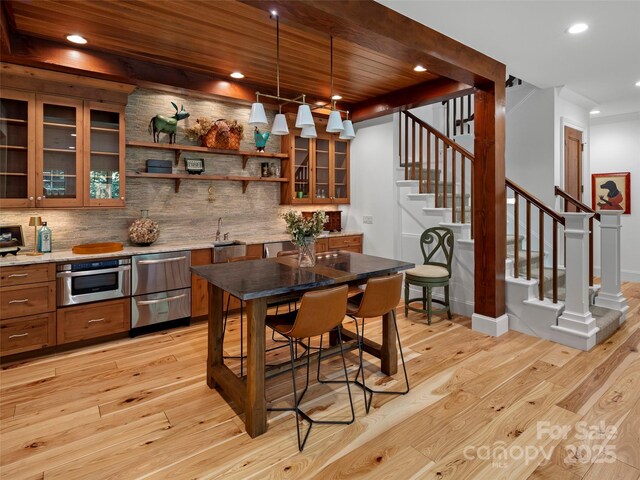 24 Deep Creek Trl, Arden, NC 28704 - kitchen with light wood finished floors, stainless steel oven, decorative backsplash, brown cabinetry, and recessed lighting