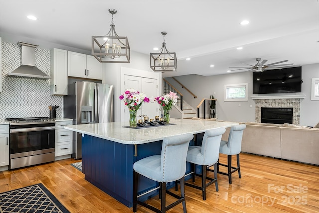 307 Hazel Mill Rd, Asheville, NC 28806 - kitchen with appliances with stainless steel finishes, wall chimney exhaust hood, tasteful backsplash, a center island, and light stone counters