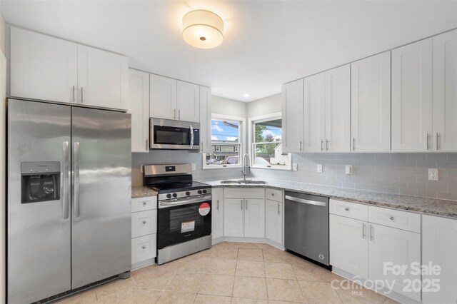 2666 Providence Dr, Gastonia, NC 28052 - kitchen with appliances with stainless steel finishes, a sink, tasteful backsplash, white cabinets, and light stone counters