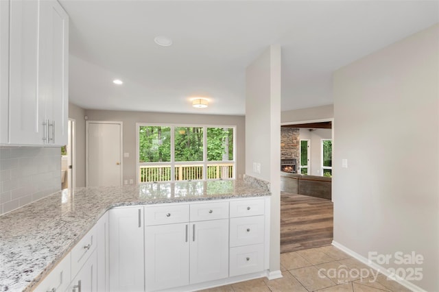 2666 Providence Dr, Gastonia, NC 28052 - kitchen with a peninsula, light stone countertops, white cabinets, tasteful backsplash, and baseboards