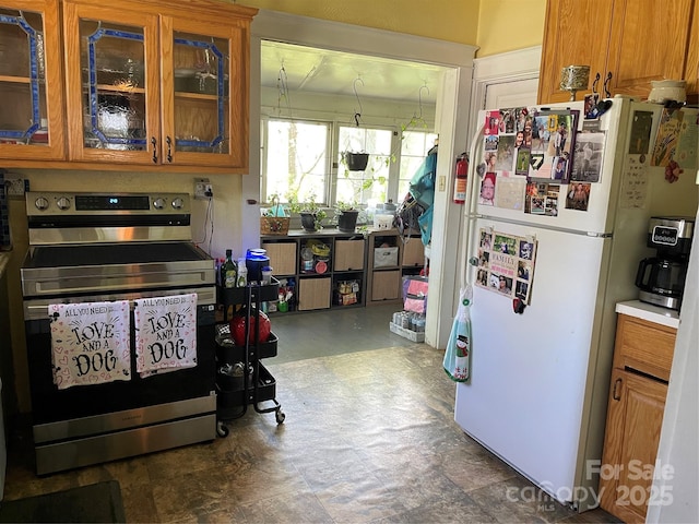 280 Walnut Ave, Spruce Pine, NC 28777 - kitchen with stainless steel electric range, freestanding refrigerator, glass insert cabinets, tile patterned floors, and brown cabinetry