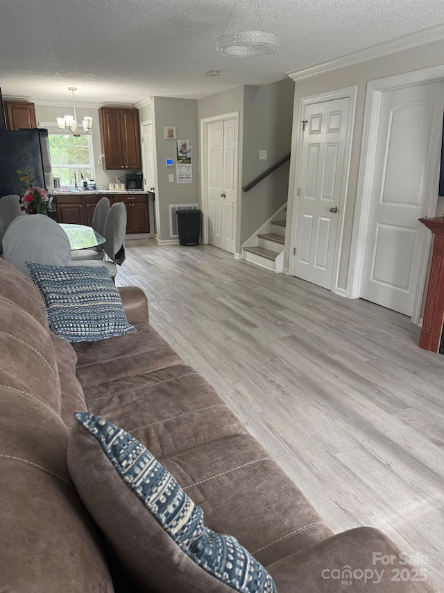 118 Fir St, Mcadenville, NC 28101 - living area with a chandelier, stairs, a textured ceiling, light wood-style floors, and ornamental molding