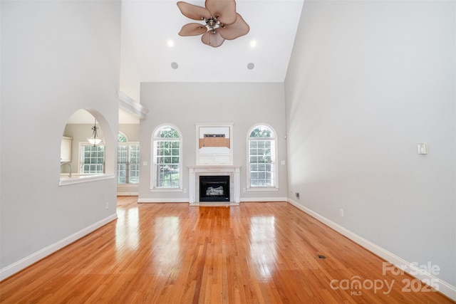 3917 Erskine Woods Dr, Bessemer City, NC 28016 - unfurnished living room with a high ceiling, ceiling fan, light wood-style flooring, baseboards, and arched walkways