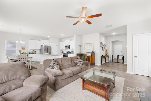 5204 Belstone Ln, Charlotte, NC 28215 - living room featuring ceiling fan, arched walkways, light wood-style floors, a chandelier, and recessed lighting