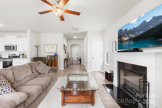 5204 Belstone Ln, Charlotte, NC 28215 - living area with ceiling fan, arched walkways, light wood-style flooring, recessed lighting, and a glass covered fireplace
