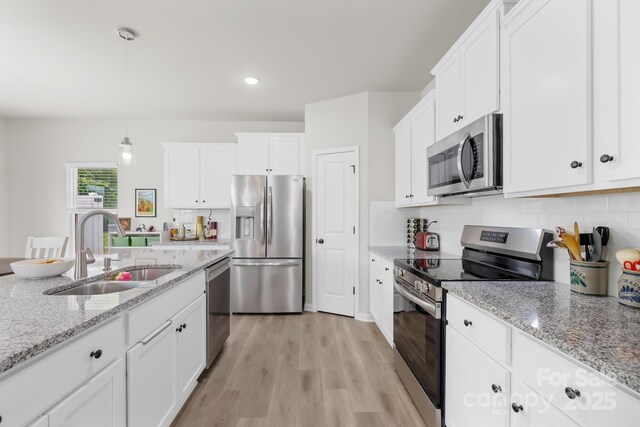 5204 Belstone Ln, Charlotte, NC 28215 - kitchen featuring appliances with stainless steel finishes, a sink, white cabinets, light wood-type flooring, and backsplash