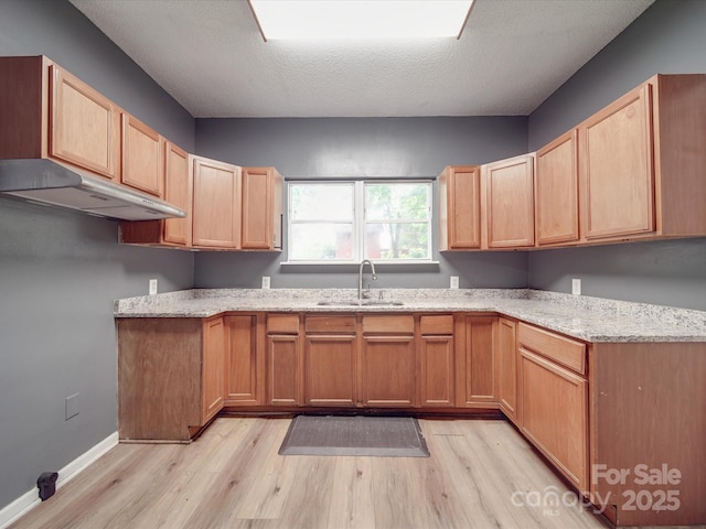 2440 Myers St, Gastonia, NC 28056 - kitchen featuring a sink, under cabinet range hood, light wood-style floors, light stone counters, and baseboards