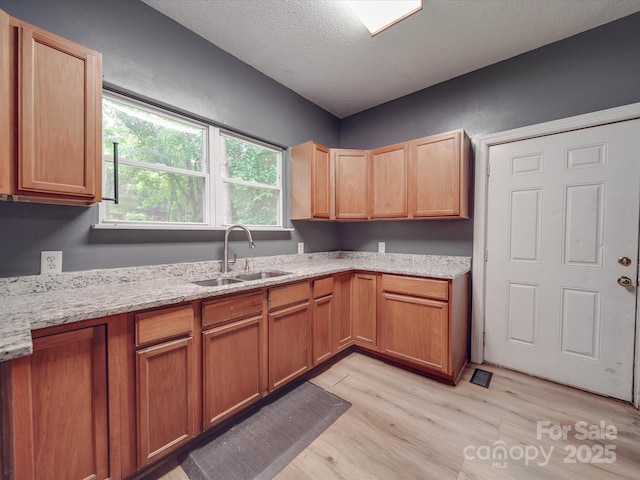 2440 Myers St, Gastonia, NC 28056 - kitchen with a sink, light wood-style floors, light stone countertops, and a textured ceiling