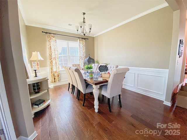 3416 Yarmouth Ln, Gastonia, NC 28056 - dining area featuring a chandelier, crown molding, dark wood-style floors, wainscoting, and a decorative wall