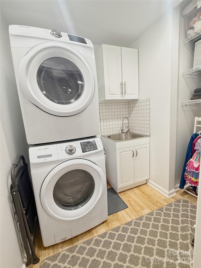 3416 Yarmouth Ln, Gastonia, NC 28056 - washroom with stacked washer and clothes dryer, light wood-type flooring, cabinet space, and baseboards