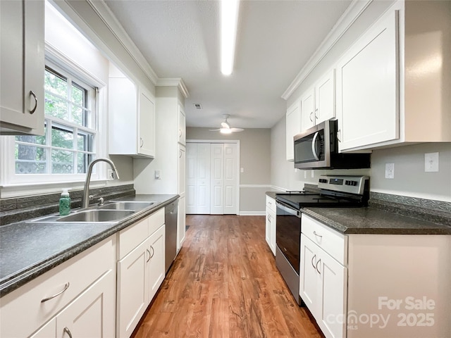 2619 Quailrush Rd, Charlotte, NC 28226 - kitchen with appliances with stainless steel finishes, a sink, white cabinets, light wood finished floors, and dark countertops