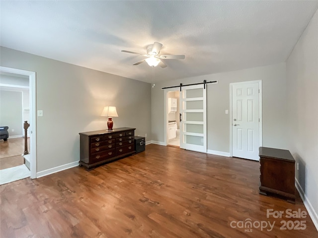 2619 Quailrush Rd, Charlotte, NC 28226 - unfurnished bedroom with a barn door, wood finished floors, baseboards, and a ceiling fan