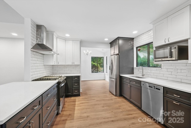 8338 Rittenhouse Cir, Charlotte, NC 28270 - kitchen featuring stainless steel appliances, wall chimney range hood, a sink, light wood-style flooring, and light countertops