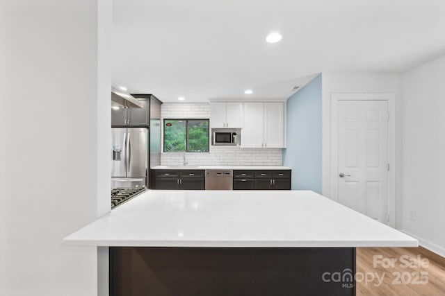 8338 Rittenhouse Cir, Charlotte, NC 28270 - kitchen with appliances with stainless steel finishes, a sink, tasteful backsplash, light countertops, and light wood-style flooring
