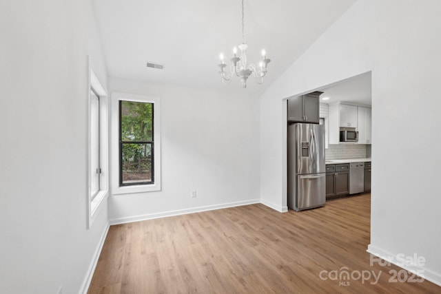 8338 Rittenhouse Cir, Charlotte, NC 28270 - unfurnished dining area featuring light wood finished floors, a chandelier, baseboards, and lofted ceiling