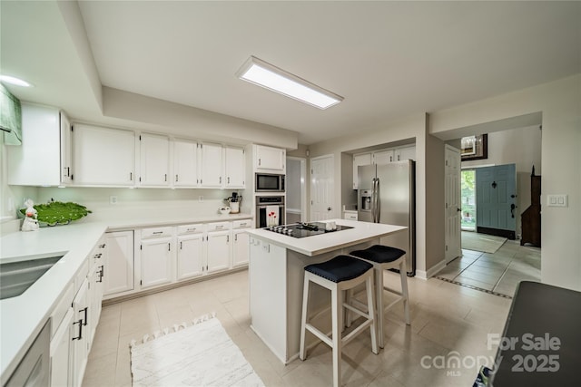 9920 White Cascade Dr, Charlotte, NC 28269 - kitchen with appliances with stainless steel finishes, light tile patterned floors, a breakfast bar area, a kitchen island, and white cabinetry