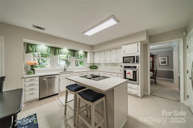 9920 White Cascade Dr, Charlotte, NC 28269 - kitchen featuring appliances with stainless steel finishes, light tile patterned floors, a sink, light countertops, and white cabinetry