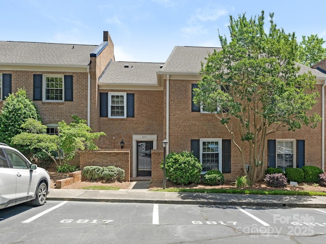 6817 Dumbarton Dr, Charlotte, NC 28210 - view of property with uncovered parking, brick siding, roof with shingles, and a chimney