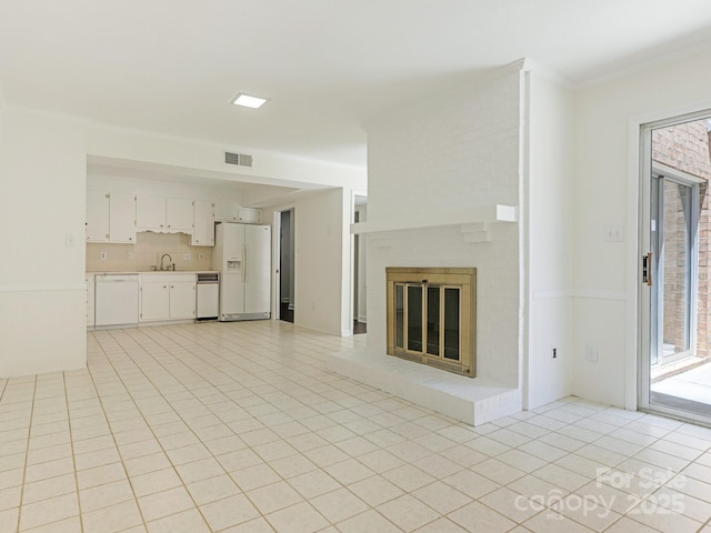6817 Dumbarton Dr, Charlotte, NC 28210 - unfurnished living room with a sink, light tile patterned floors, crown molding, and a fireplace