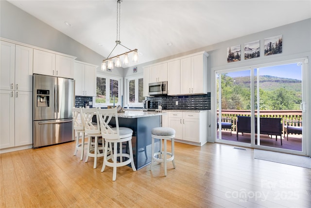 21 Kylie Grace Ln, Candler, NC 28715 - kitchen with appliances with stainless steel finishes, lofted ceiling, decorative backsplash, a breakfast bar area, and white cabinetry