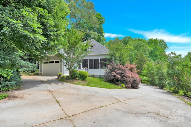 267 Ikerd Dr SE, Concord, NC 28025 - view of property hidden behind natural elements with driveway, an attached garage, a shingled roof, and a sunroom