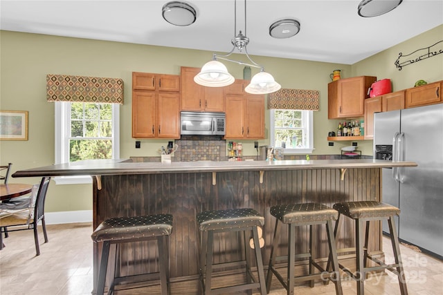 267 Ikerd Dr SE, Concord, NC 28025 - kitchen featuring stainless steel appliances, tasteful backsplash, a kitchen bar, pendant lighting, and brown cabinets
