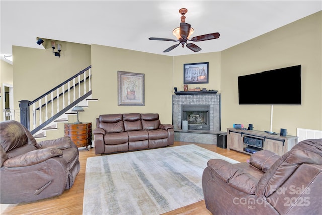 267 Ikerd Dr SE, Concord, NC 28025 - living room with a ceiling fan, light wood-style floors, a tiled fireplace, and stairway