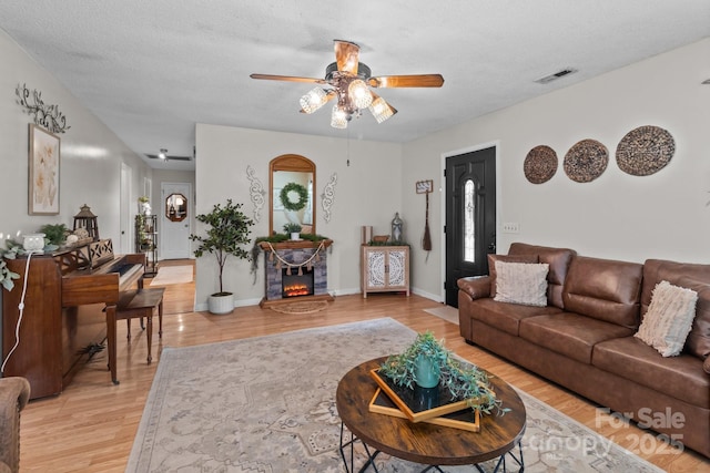 716 Mooresville Rd, Salisbury, NC 28144 - living area with a ceiling fan, light wood-style flooring, a fireplace, and a textured ceiling