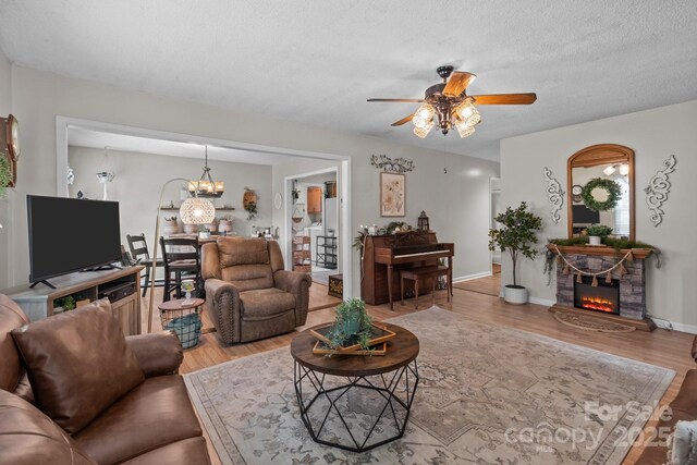 716 Mooresville Rd, Salisbury, NC 28144 - living room featuring a ceiling fan, wood finished floors, a fireplace, a chandelier, and baseboards