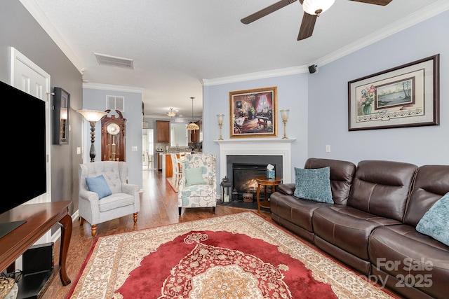 411 Summergate Dr Unit 78, Winston Salem, NC 27103 - living area featuring a ceiling fan, wood finished floors, ornamental molding, a fireplace with flush hearth, and a textured ceiling