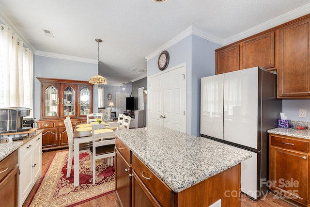 411 Summergate Dr Unit 78, Winston Salem, NC 27103 - kitchen with freestanding refrigerator, wood finished floors, ornamental molding, a center island, and light stone counters