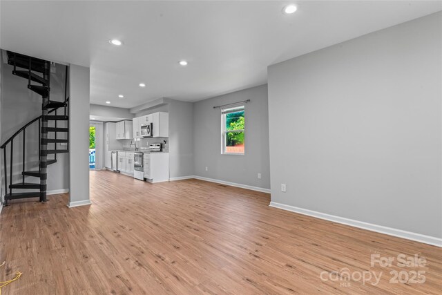 146 Georgia St SW, Concord, NC 28025 - unfurnished living room featuring stairs, recessed lighting, plenty of natural light, and light wood-style floors