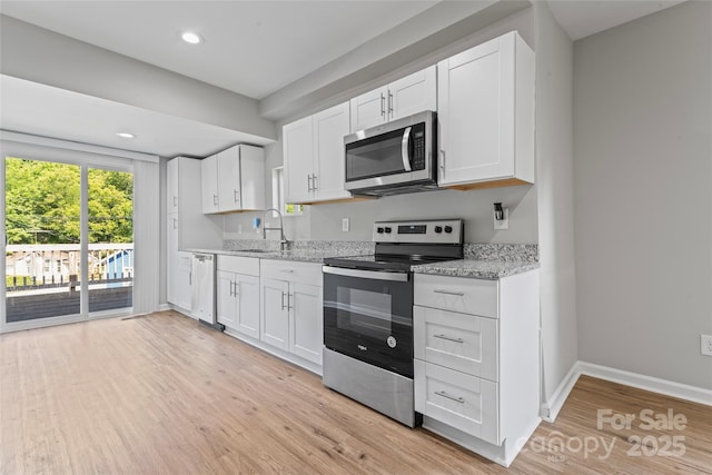 146 Georgia St SW, Concord, NC 28025 - kitchen with appliances with stainless steel finishes, light wood-style floors, white cabinetry, light stone countertops, and recessed lighting