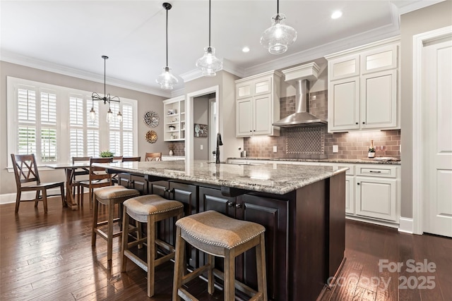 9125 Dylan Ridge Ct, Concord, NC 28027 - kitchen featuring wall chimney exhaust hood, a sink, white cabinets, ornamental molding, and backsplash