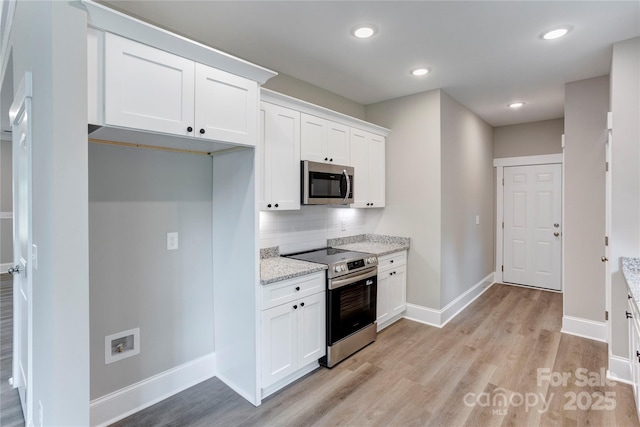 501 Old Speedway Dr NW Unit 1, Concord, NC 28027 - kitchen with stainless steel appliances, baseboards, light wood-type flooring, decorative backsplash, and white cabinets