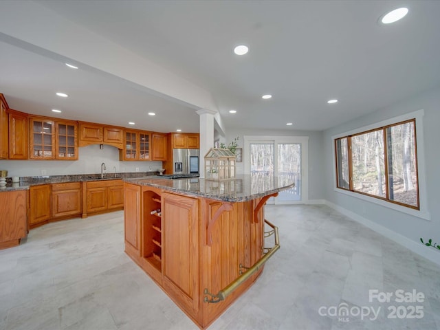 2143 Manawa Ln, Tega Cay, SC 29708 - kitchen featuring a kitchen island, recessed lighting, brown cabinets, stainless steel refrigerator with ice dispenser, and dark stone countertops