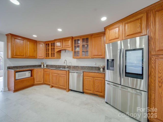 2143 Manawa Ln, Tega Cay, SC 29708 - kitchen featuring appliances with stainless steel finishes, brown cabinetry, a sink, glass insert cabinets, and recessed lighting