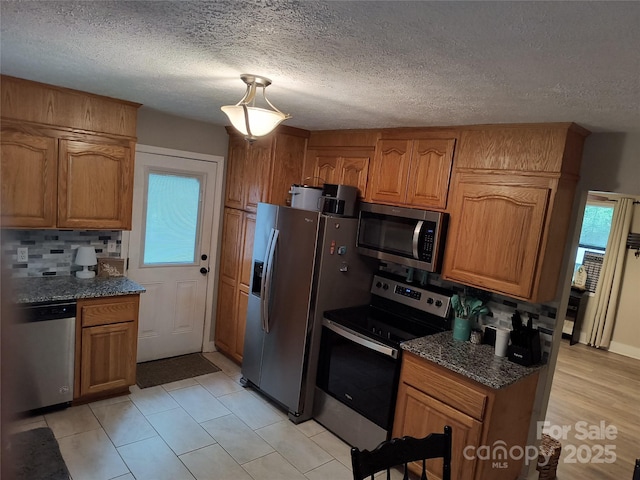 500 Bob Rollins Rd, Forest City, NC 28043 - kitchen with stainless steel appliances, brown cabinetry, healthy amount of natural light, decorative backsplash, and a textured ceiling