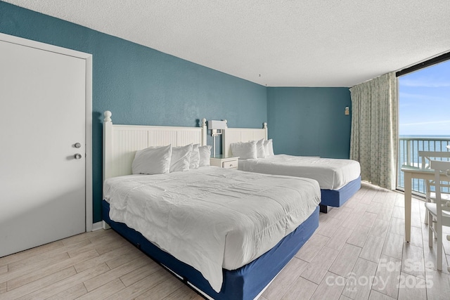 9550 Shore Dr Unit 930, Myrtle Beach, SC 29572 - bedroom with expansive windows, a textured ceiling, wood finished floors, and a textured wall