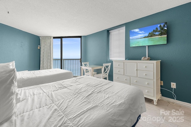 9550 Shore Dr Unit 930, Myrtle Beach, SC 29572 - bedroom featuring light wood-style flooring, a textured ceiling, baseboards, a textured wall, and expansive windows