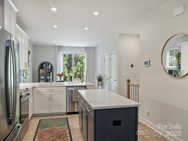 513 Cubitt Ct, Charlotte, NC 28205 - kitchen featuring appliances with stainless steel finishes, a peninsula, light wood-style floors, white cabinetry, and recessed lighting