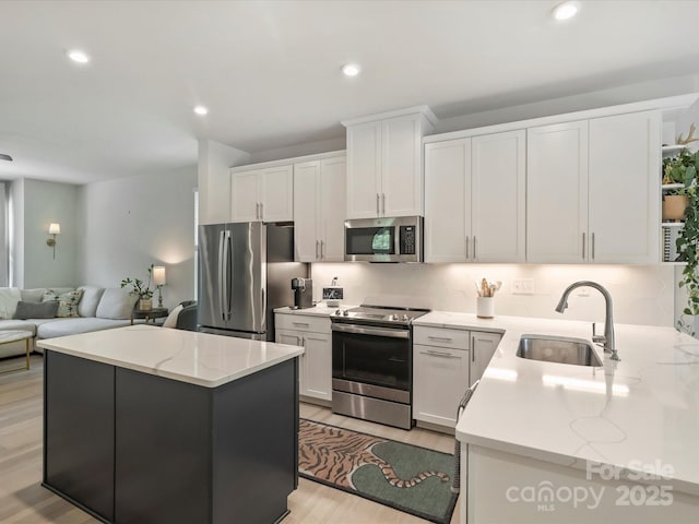 513 Cubitt Ct, Charlotte, NC 28205 - kitchen featuring appliances with stainless steel finishes, a sink, white cabinets, light wood-type flooring, and open floor plan