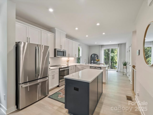 513 Cubitt Ct, Charlotte, NC 28205 - kitchen featuring appliances with stainless steel finishes, a peninsula, light countertops, a center island, and white cabinetry