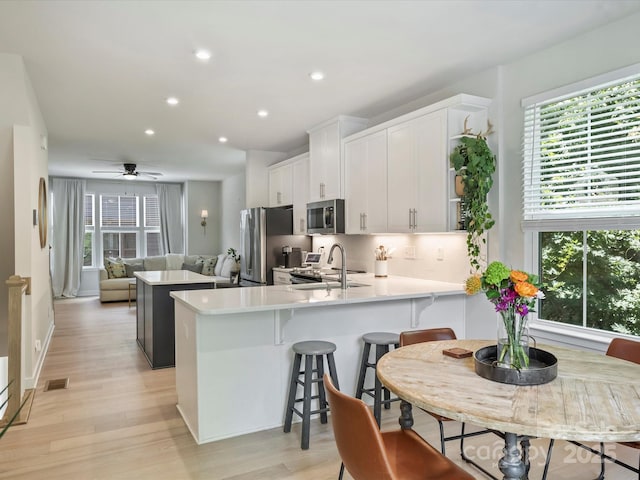 513 Cubitt Ct, Charlotte, NC 28205 - kitchen with stainless steel appliances, a sink, a kitchen island, light wood-type flooring, and white cabinetry