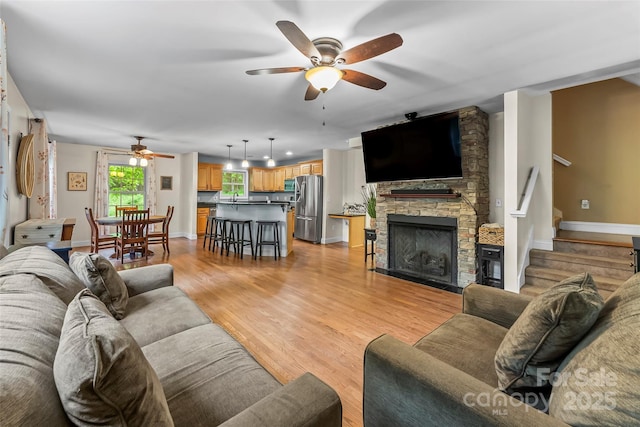 32 Evita Cove Rd, Weaverville, NC 28787 - living room with ceiling fan, baseboards, stairs, a stone fireplace, and light wood finished floors