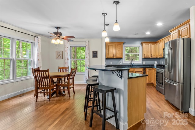 32 Evita Cove Rd, Weaverville, NC 28787 - kitchen featuring appliances with stainless steel finishes, dark countertops, light wood-type flooring, a breakfast bar area, and plenty of natural light