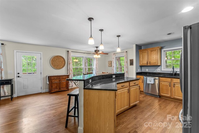 32 Evita Cove Rd, Weaverville, NC 28787 - kitchen with appliances with stainless steel finishes, a sink, a kitchen bar, light wood-style flooring, and a kitchen island