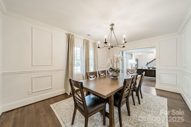 1121 S Wendover Rd, Charlotte, NC 28211 - dining area with a chandelier, a decorative wall, dark wood-style floors, crown molding, and stairway