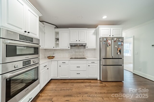 1121 S Wendover Rd, Charlotte, NC 28211 - kitchen with stainless steel appliances, under cabinet range hood, crown molding, decorative backsplash, and light countertops