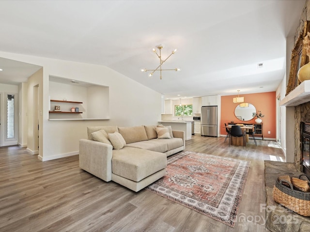 3531 Bon Rea Dr, Charlotte, NC 28226 - living room with light wood-style floors, a chandelier, a glass covered fireplace, baseboards, and vaulted ceiling